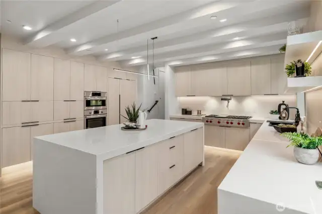 An oversized waterfall quartz island, complete with ample storage, serves as the stunning anchor of the kitchen.