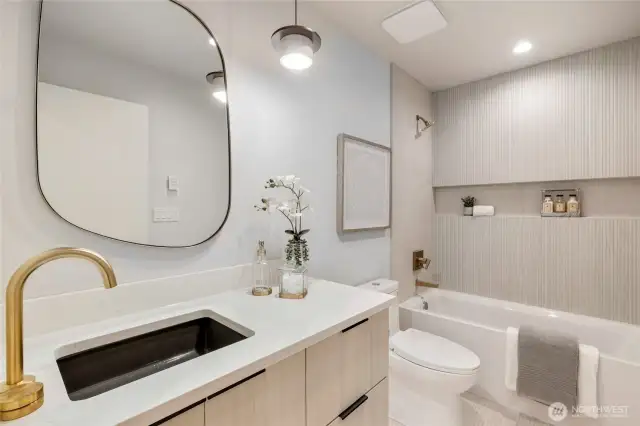 Chic Bath Design: The tub shower, complete with a tiled surround and a convenient niche, combines style with practicality.