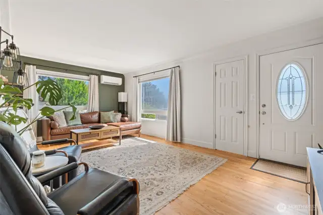 Living area  large windows and warm hardwood floors.