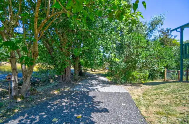 Driveway extended to make it circular or added parking. Where driveway comes out to the road past the trees would also be the entrance for path to bring vehicles or RV's to the filed area.
