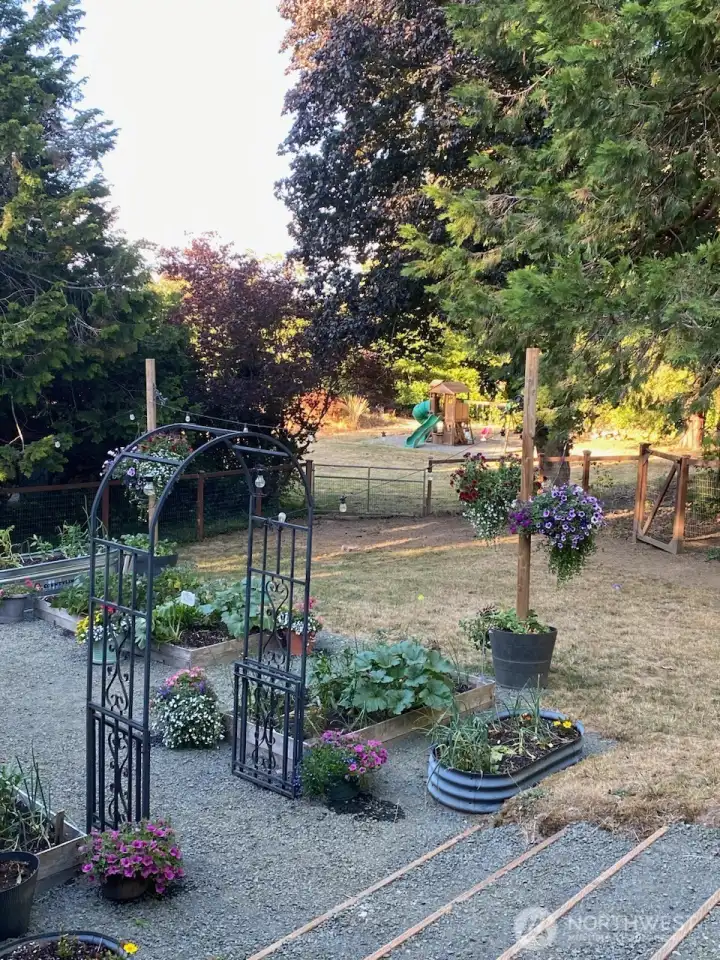 One more view from the base of the deck looking at the back yard, garden area, the the field with play structure beyond the fence.