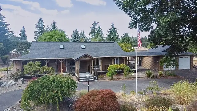 Charming, covered porch framed by mature landscaping.
