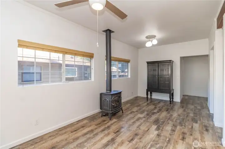 The living and dining area features a free-standing gas stove and beautiful flooring throughout the home.