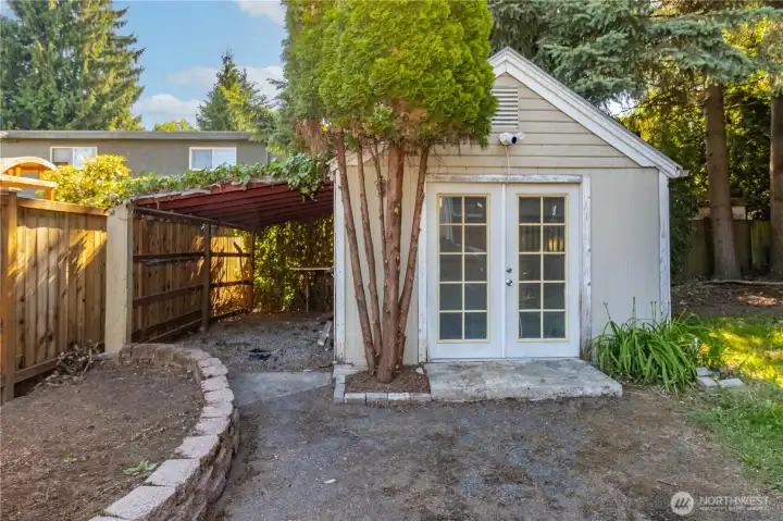 Studio includes an attached covered area for yard tools or flexible storage use.
