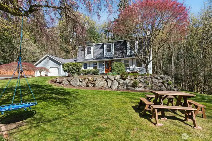 Well-maintained landscaping complemented by a park bench and multiple swings throughout the property.