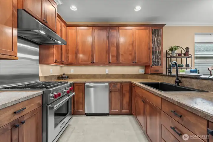 Chef’s kitchen featuring Wolf range, Amana refrigerator, Miele dishwasher, granite countertops, custom cabinetry, and Kohler fixtures.
