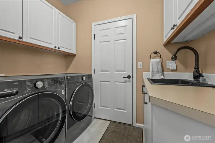 Utility room off the kitchen with sink, storage cabinets, and LG washer and dryer included.