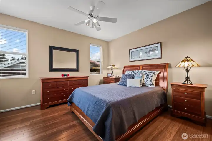 Spacious primary suite with bamboo floors, large windows, and room for a king-size bed.