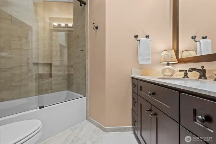 Adjacent remodeled full bath featuring tile flooring, a tiled tub/shower surround, granite countertops, and a beautiful vanity with ample storage.