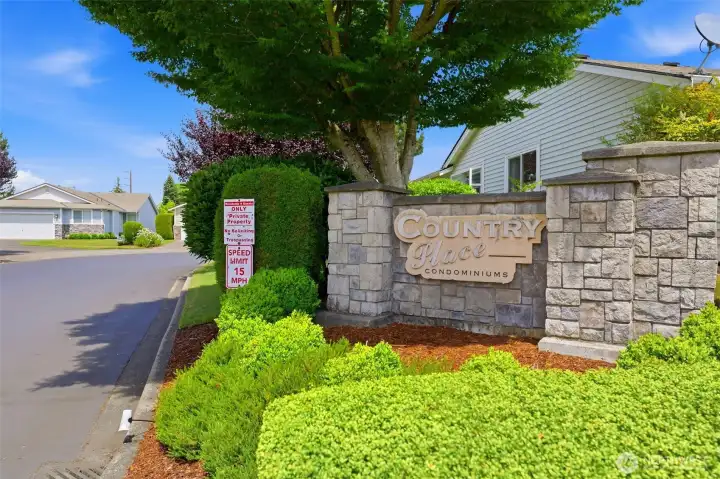 Welcoming stone entrance to Country Place Condominiums — a well-kept, established Lakewood community with manicured landscaping throughout.