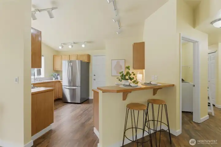 Breakfast bar seating and an adjacent laundry room with newer washer and dryer — everyday convenience, thoughtfully arranged.