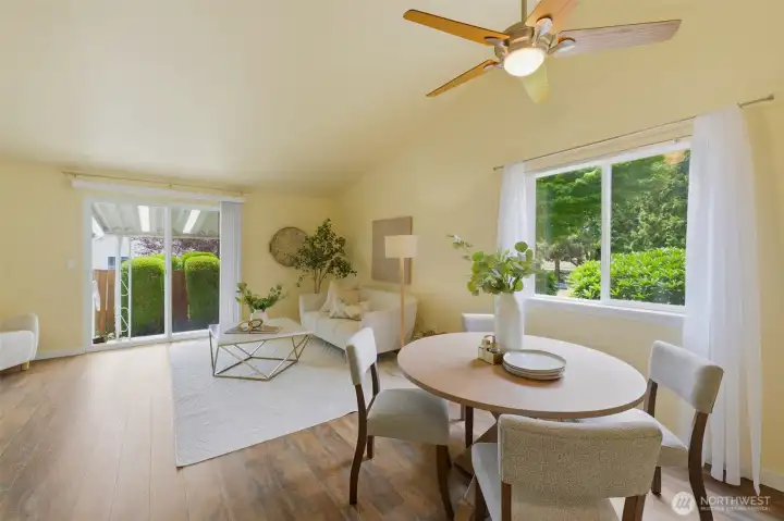 Light-filled open-concept dining and living area with vaulted ceiling, ceiling fan, and sliding door to the private covered patio. Staging by Details.