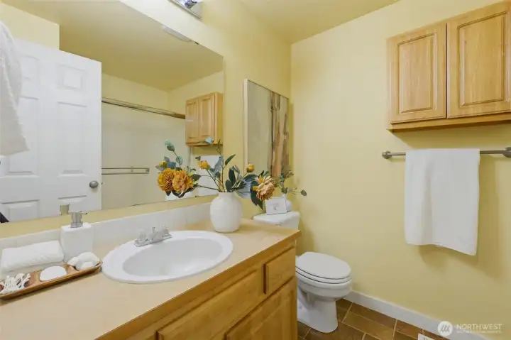 Bright full guest/hallway bath with generous vanity, tile accents, and bonus cabinet storage.