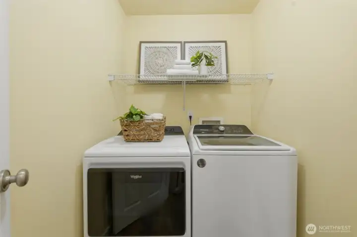 Convenient in-unit laundry room with shelving and included washer and dryer.