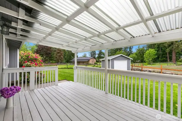 Covered back deck overlooks tranquil back yard.
