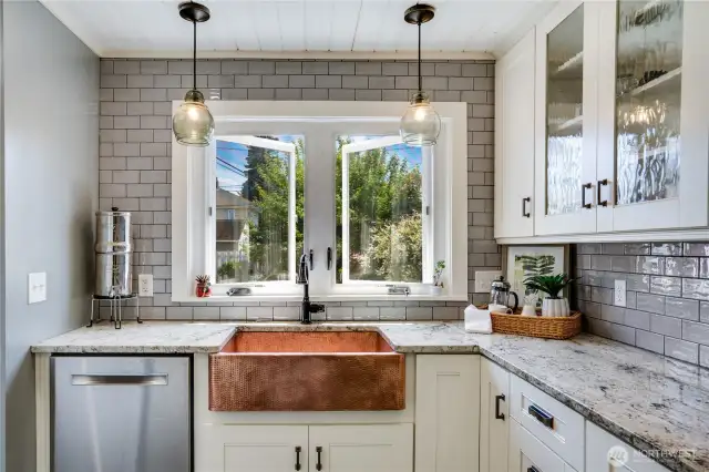 This kitchen is a detailed dream, featuring full tile backsplash, a shiplap ceiling that enhances the character of the space, glass fronted cabinetry, and a copper farm sink serving as a striking focal point. Granite countertops complete the look, providing both elegance and lasting quality.