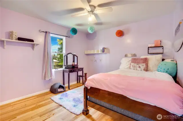 One of the additional main floor bedrooms features beautifully refinished hardwood floors, a bright window that fills the space with natural light, and a convenient closet for easy storage