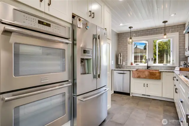 Designed for culinary enthusiasts, this kitchen boasts double ovens—perfect for homecooked meals and entertaining. Notice the conveniently located pantry next to the refrigerator and the abundance of cabinetry above.
