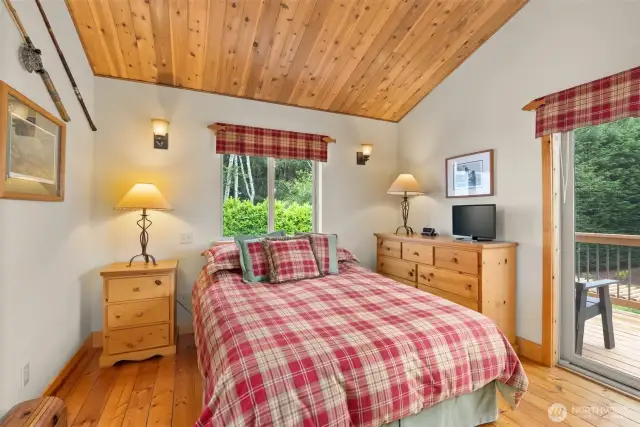 Primary bedroom with balcony overlooking the rear garden and forest