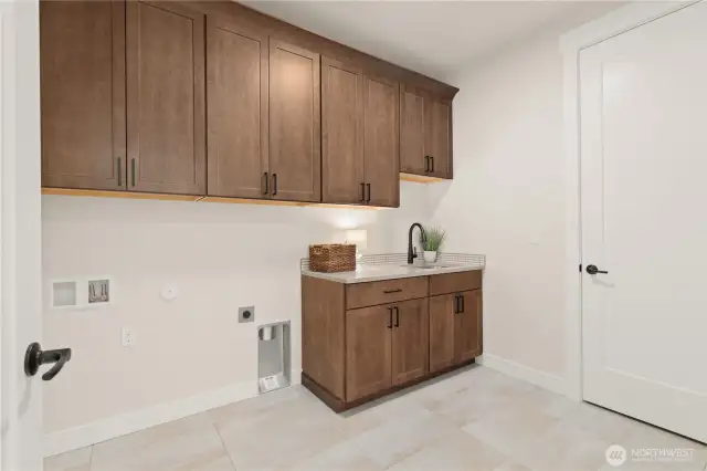 This spacious Laundry room makes washday a joy! with cabinetry to hide all of your laundry needs and Counter space for folding.