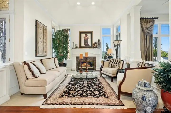 An elegant living room featuring detailed crown molding, architectural columns, and a welcoming fireplace