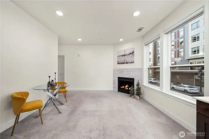 A wide angle of the living room reveals flexible space for relaxing or entertaining. The neutral palette provides a clean backdrop and pairs beautifully with the bright windows and cozy fireplace.