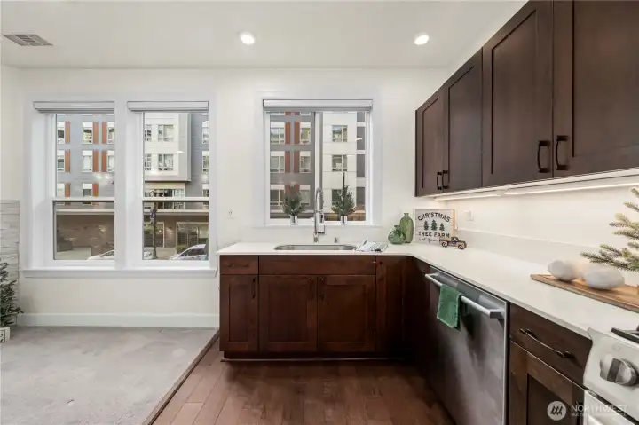 Expansive windows frame the prep area, brightening the kitchen and creating an inviting atmosphere. The extended countertop offers generous room for cooking, baking, or setting up a casual serving area.