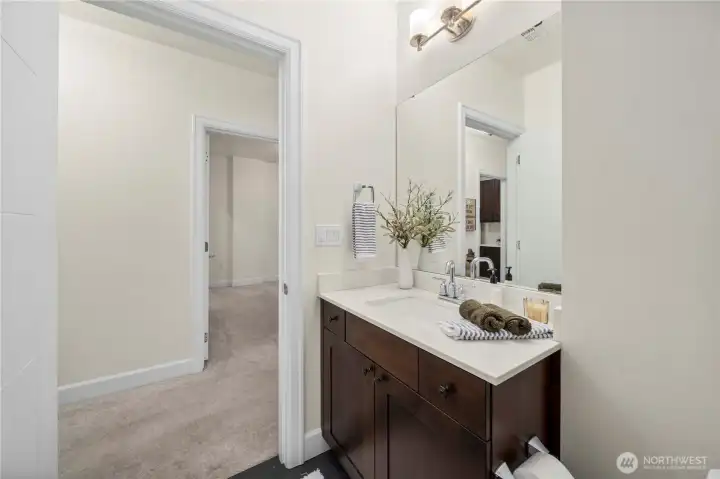 This view highlights the convenient hallway location of the main full bath, ideal for guests or everyday use. The broad vanity, updated fixtures, and generous mirror enhance both function and style, complementing the home’s cohesive finishes.