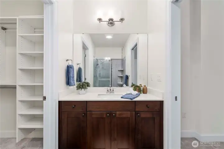 The 3/4 ensuite bathroom features a wide vanity with ample counter space, rich cabinetry, and a large mirror that enhances the room’s bright, clean feel. Modern fixtures and thoughtful storage support everyday convenience.