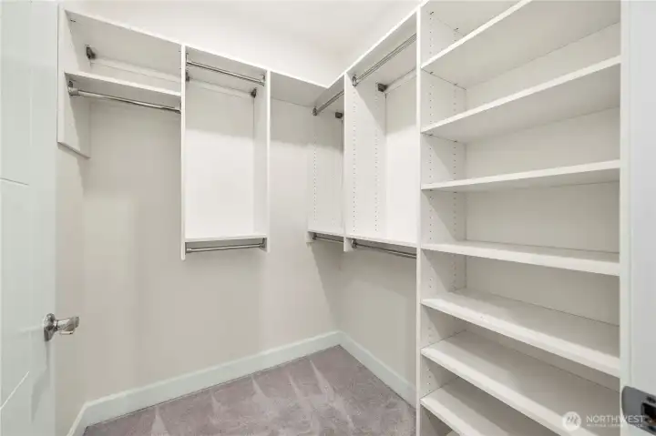 The primary suite includes a large walk-in closet equipped with extensive shelving and multiple hanging sections, providing organized storage for clothing, accessories, and daily essentials.