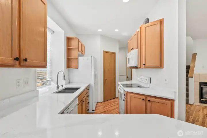 Beautiful new countertops make the kitchen feel extra bright. Stainless sink with double compartments, with window looking out to side yard. Dishwasher located next to sink and across kitchen from glass-top stove/range and microwave. Laminate hardwood flooring throughout main floor.