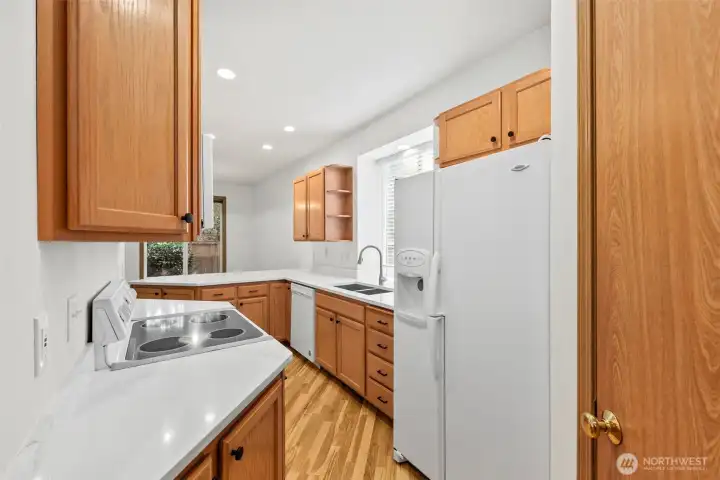 Kitchen with update counters and abundant natural light, matching white appliances, and pantry closet. Laminate hardwood flooring throughout main floor.