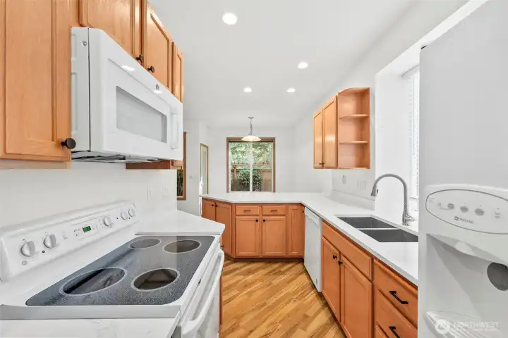 White matching Kitchen appliances including an above-stove microwave, dual-side refridgerator, dishwasher and glass-top stove/range. Laminate hardwood flooring throughout main floor.