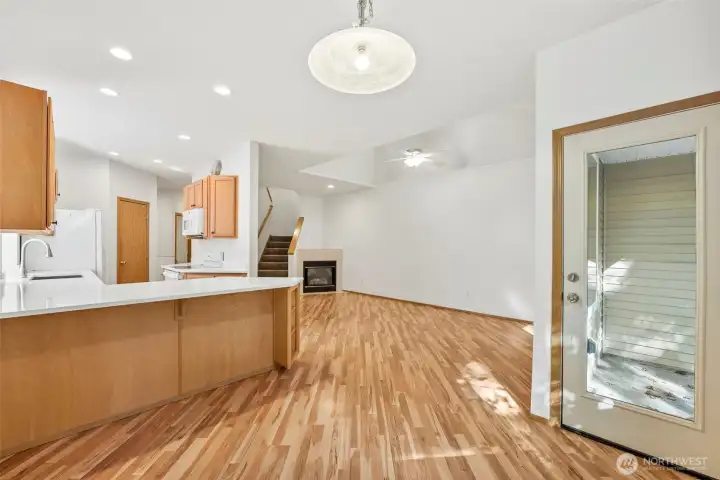 Dining room looking out to Living room, kitchen and backyard/patio window door to bring in even more natural light to the space. Laminate hardwood flooring throughout main floor.