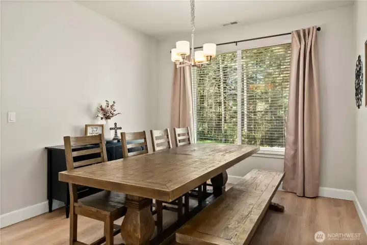 Dining room with LVP flooring and chandelier light fixture. Large window floods the room with light.