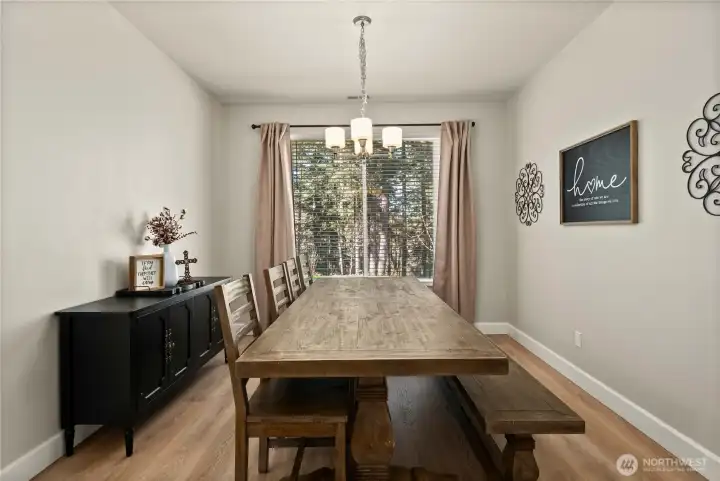 Dining room with LVP flooring and chandelier light fixture. Large window floods the room with light.
