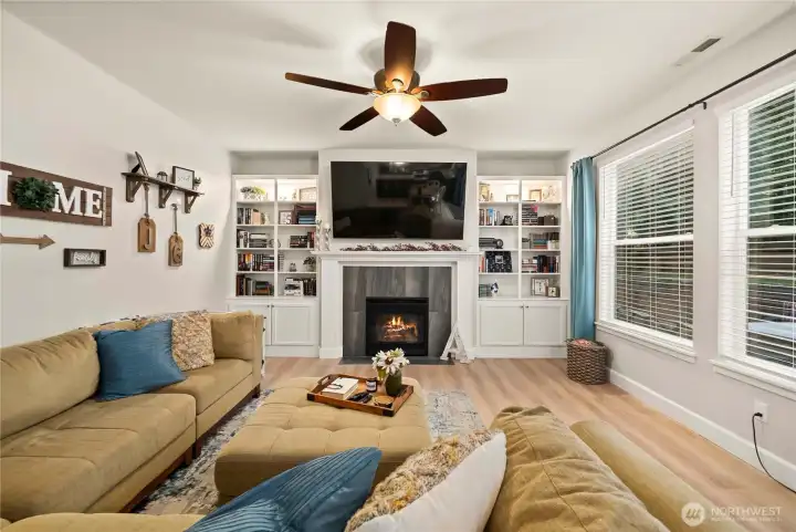 Living room located at the rear of the house, full of natural light, featuring beautiful built-ins along side the fireplace, and LVP flooring.