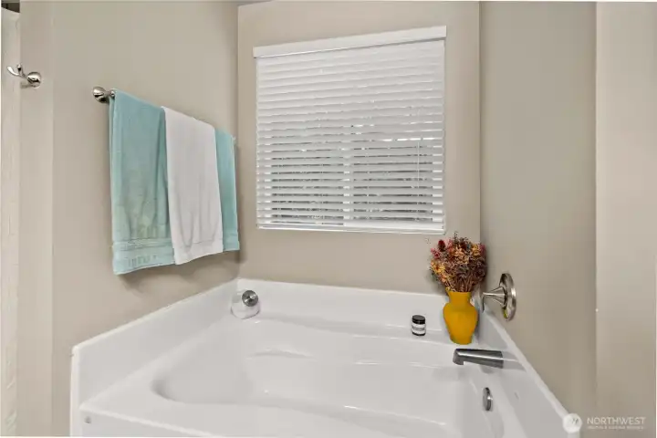 Primary en-suite soaking tub situated between the walk-in shower and toilet. The window over the tub brings in natural light for your relaxing soak. Conveniently located towel rack installed above tub. Wall mount faucet fixtures.