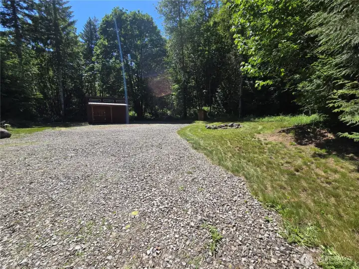 Looking south towards the large shed and future shop sight. Fire pit ring on the right. The second power box with RV and 110 outlets is just beyond the Rock at the left edge of the photo.