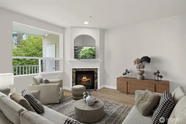 Virtually staged living room with gas fireplace and picture window to the peaceful greenbelt area