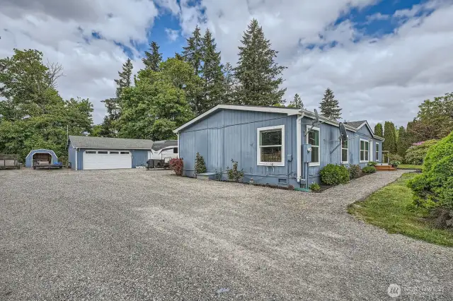 Another view of the ample parking area. The shed to the left is great for storing yard necessities. The two-car garage has a shop area extra storage or work space.