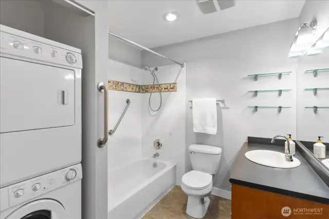 Huge bath with laundry, grab bars, and vinyl flooring.
