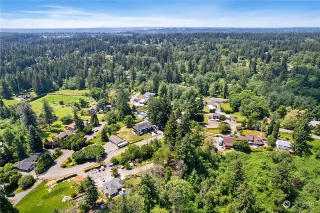 View to the NW-West with the East hillside and the South (left) and North (right) neighbors' lots in view.  Subject property has the Tall evergreens perched to the right of the house with large lawn & parked cars in lower portion of photo.