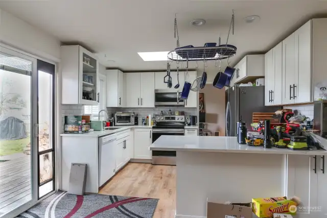 Kitchen with eat-in bar connects to a sliding door going out to the  Backyard deck.