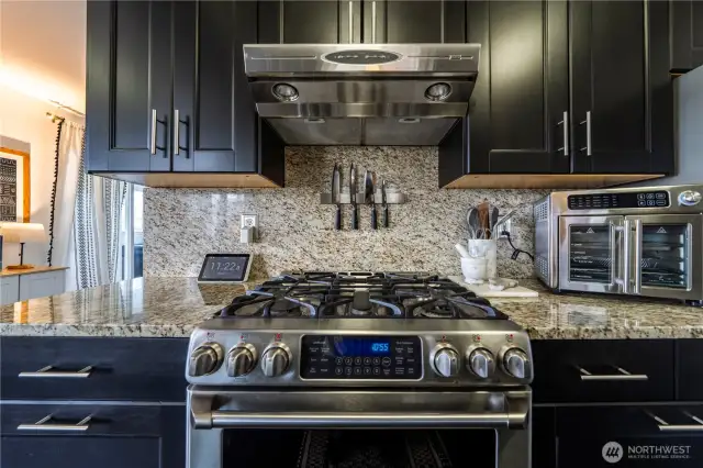 A beautifully designed kitchen featuring a gas range, double ovens, and a stainless steel hood for a polished look.