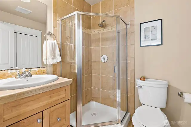 This guest bathroom has floor to ceiling tiled shower, matching vanity and coordinated flooring designed to enhance the overall look. Additionally, there is a large storage closet perfect for those large items like a vacuum.