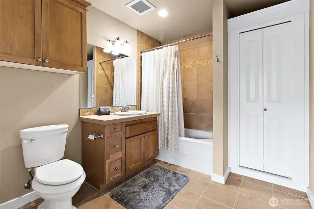 The Primary full bath has a tiled vanity with a tiled bath/shower combination creating a cohesive and modern look.  A dedicated linen closet offers practical storage space and a custom built-in cabinet for all those items you need but never have enough space.