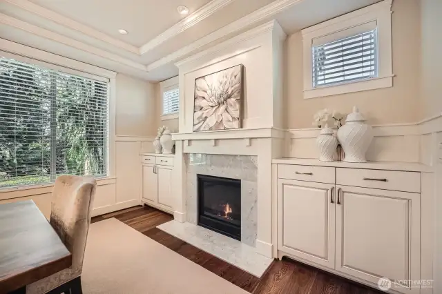 Dining room fireplace features a marble surround with painted white wood detailing on the mantle and corbels, blending elegance with classic charm.