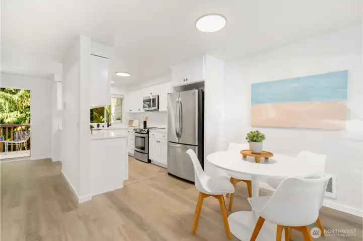 Stylish kitchen and dining area with stainless steel appliances, white cabinetry, and direct access to the outdoor deck.