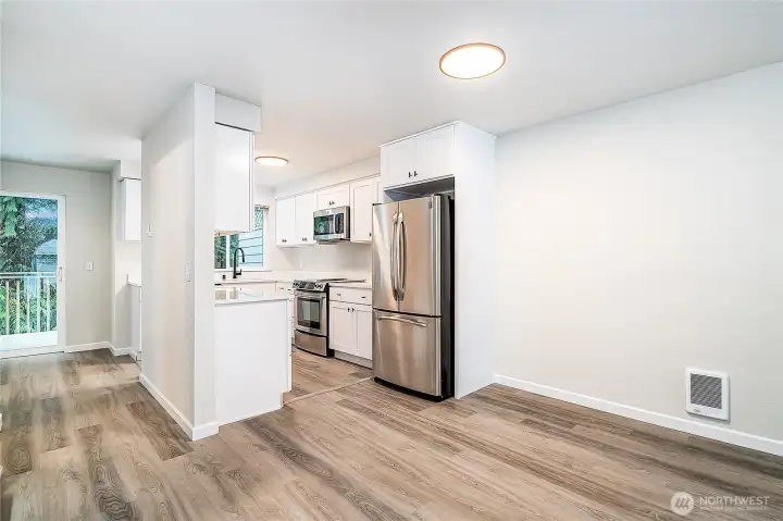 Stylish kitchen and dining area with stainless steel appliances, white cabinetry, and direct access to the outdoor deck.